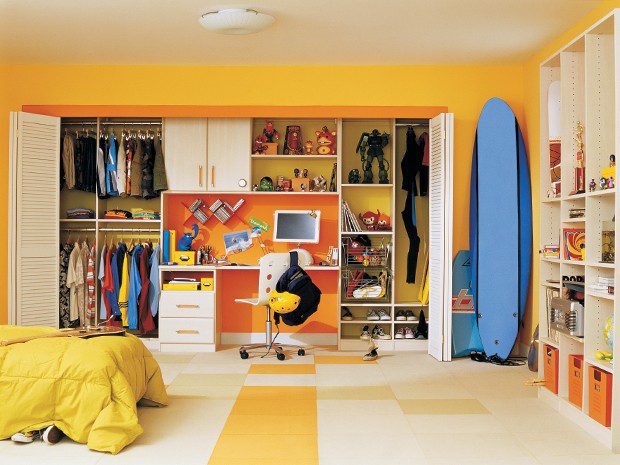 Kids' Reach in closet with work desk, cabinets, hanging poles, shoe storage and additional open shelving in a wood grain finish with bright accents by California Closets