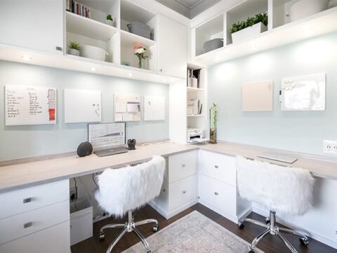 Corner desks in home office with custom cabinets, shelves, and LED lighting by California Closets 