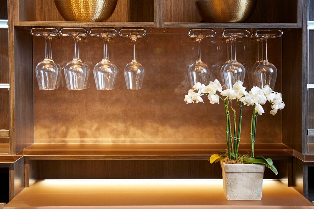 Detalles de almacenamiento para la cristalería del bar de vinos para el hogar con un diseño de ecorresina en la pared trasera e iluminación led de California Closets