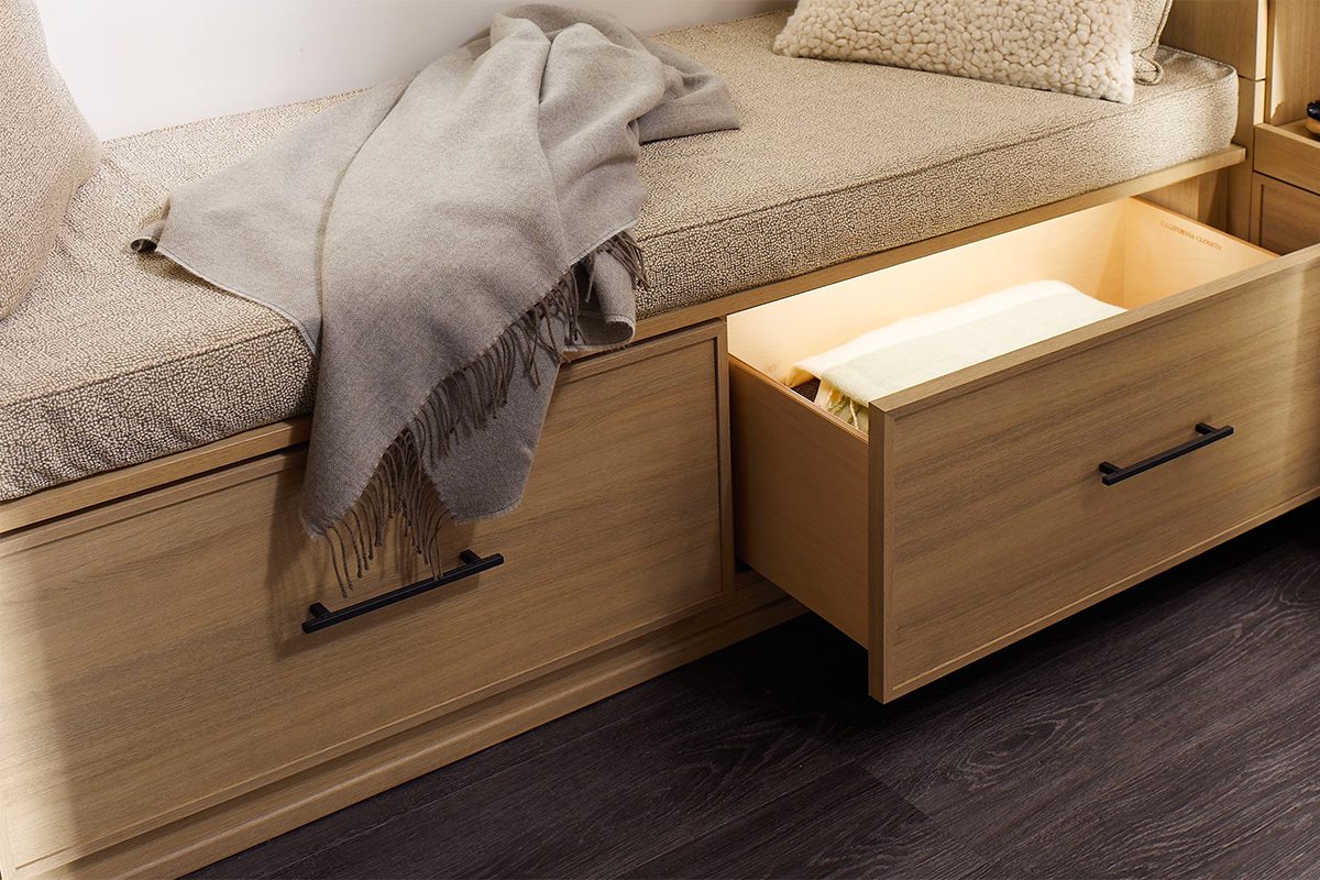Custom drawers in natural wood grain finish with internal led lighting by California Closets