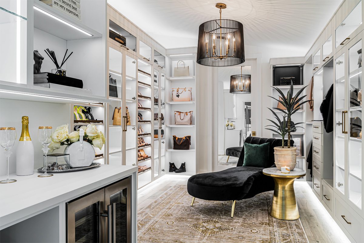 Luxury walk in closet with shoe storage and custom led lighting throughout by California Closets