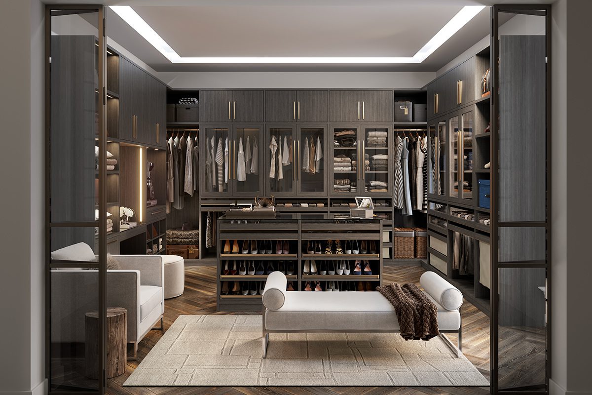 Closet design in u-shape in modern dark wood grain finish with custom shoe storage, glass door cabinets and center seating by California Closets